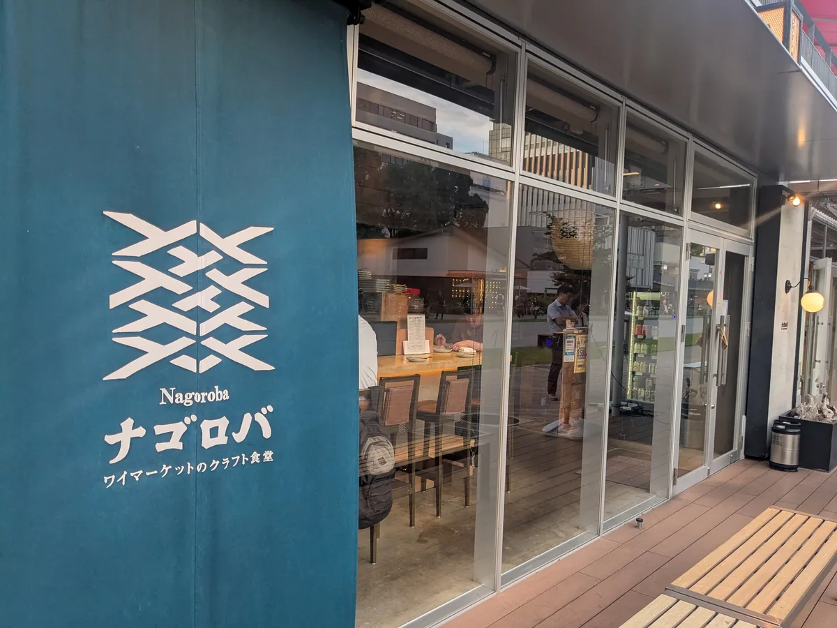 昼の久屋大通パークに面したナゴロバの入口。藍色の暖簾とガラス張りの明るい店内