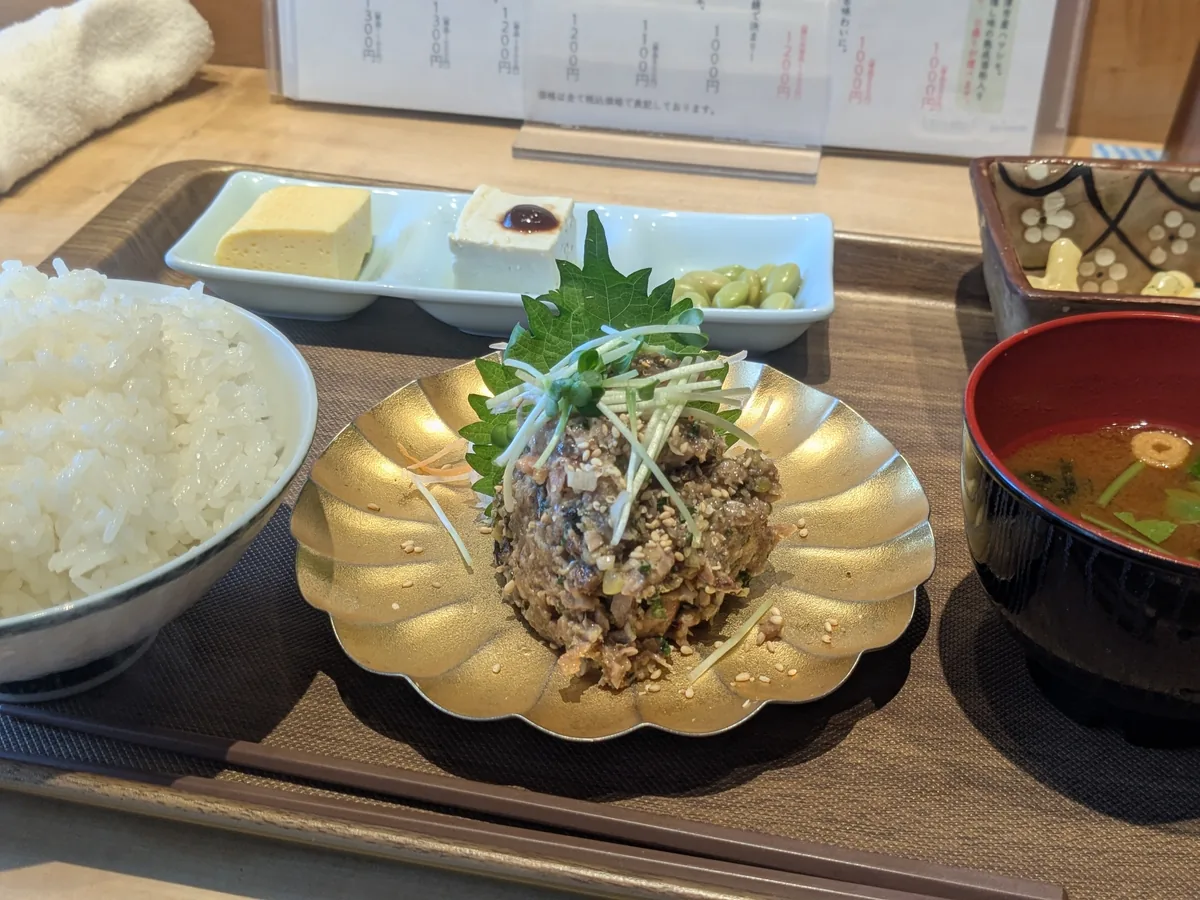 ナゴロバの「カツオの醤油麹なめろう」を金の小皿に盛り付けた一品。大葉と白髪ねぎ、白ごまをあしらった発酵料理