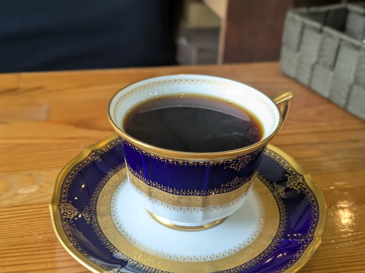 とよのcoffeeの黒ブレンドコーヒー、青と金の上品なカップに注がれた深煎り