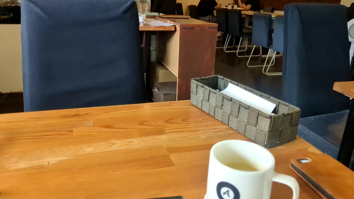 とよのcoffeeの店内、木のテーブルとネイビーの椅子が並ぶ落ち着いた空間