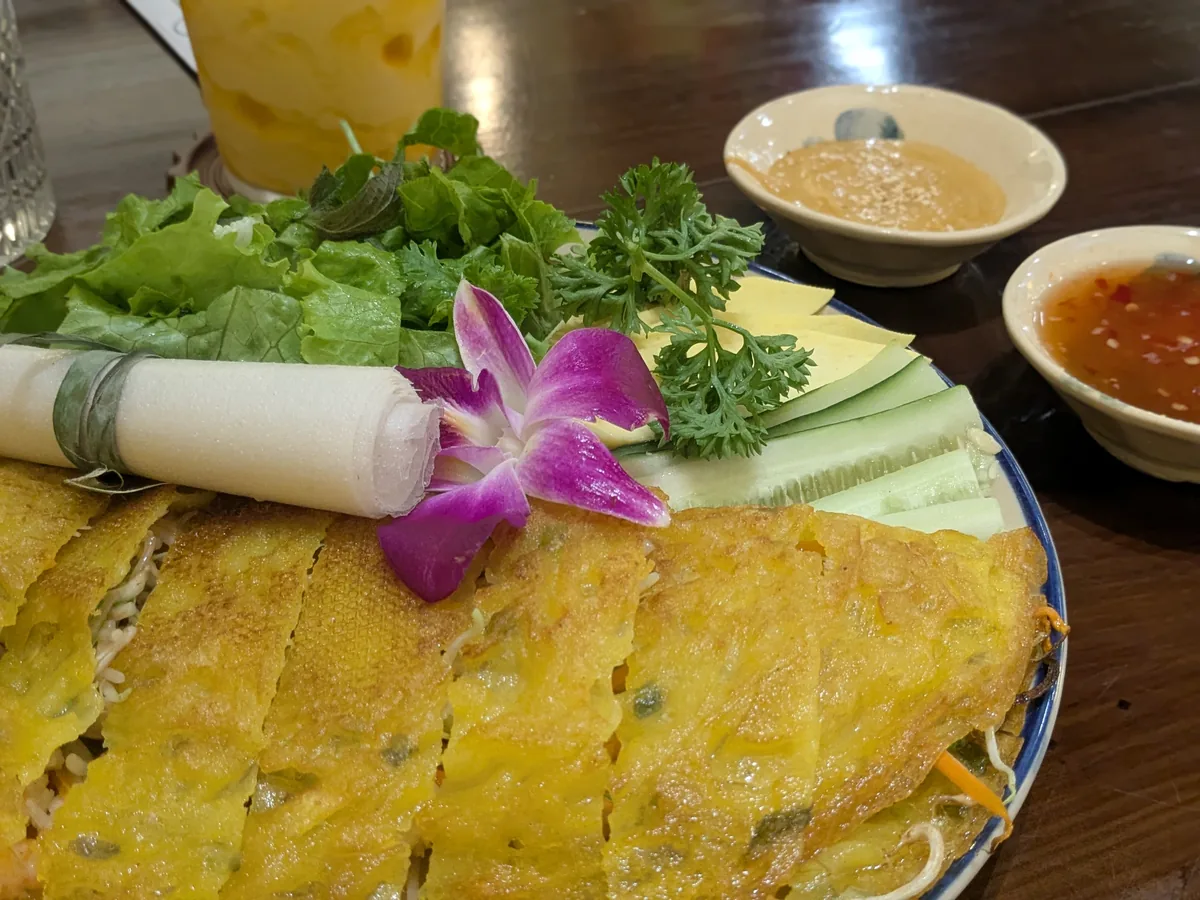野菜とライスペーパーが添えられたベトナム風お好み焼きバインセオ
