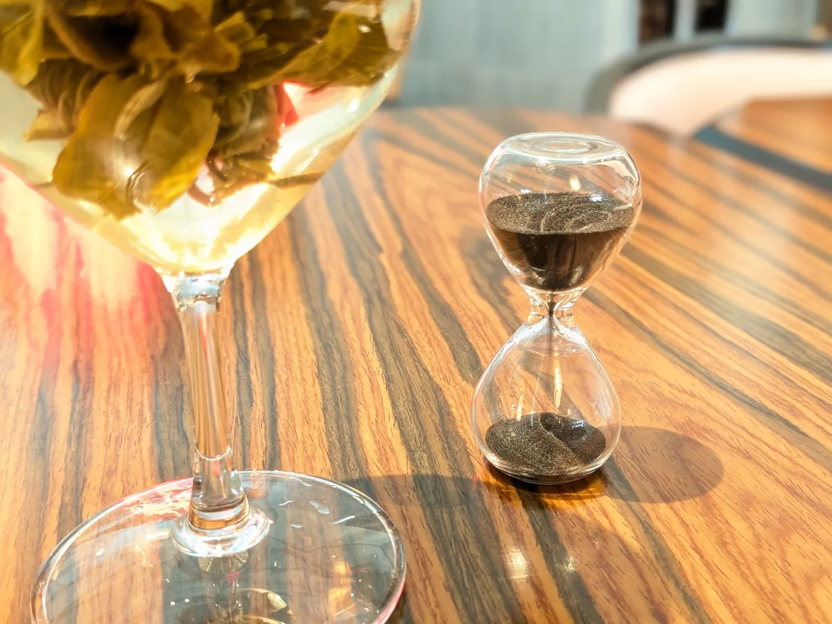 LIANHUAの工芸茶に添えられた砂時計。木目のテーブルの上で待ち時間を計る