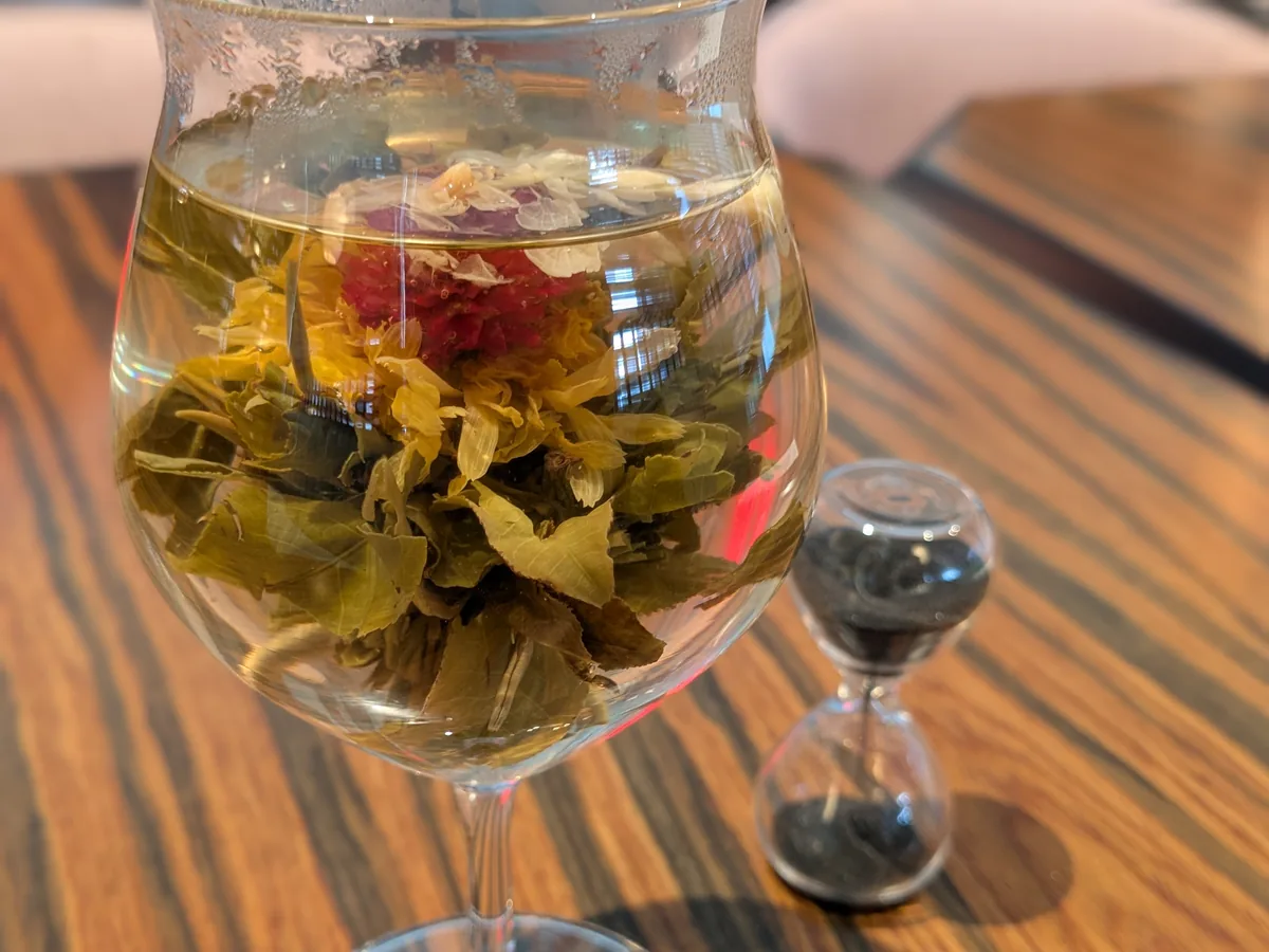 LIANHUA(蓮花)の工芸茶「双龍吐珠」。グラスの中でジャスミンの白い花と赤い花が開いている