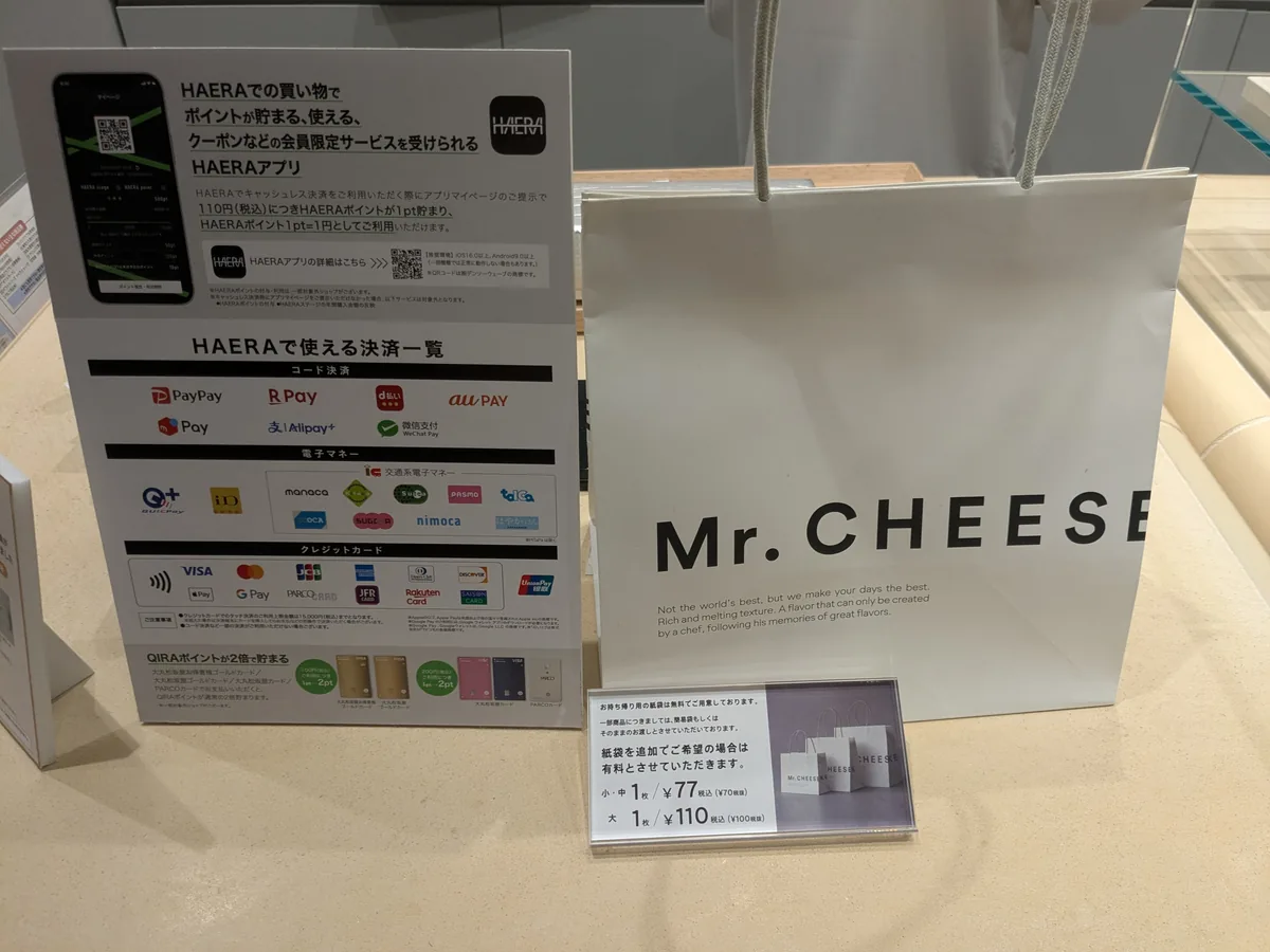 HAERAで使える決済一覧の案内板とMr. CHEESECAKEの紙袋