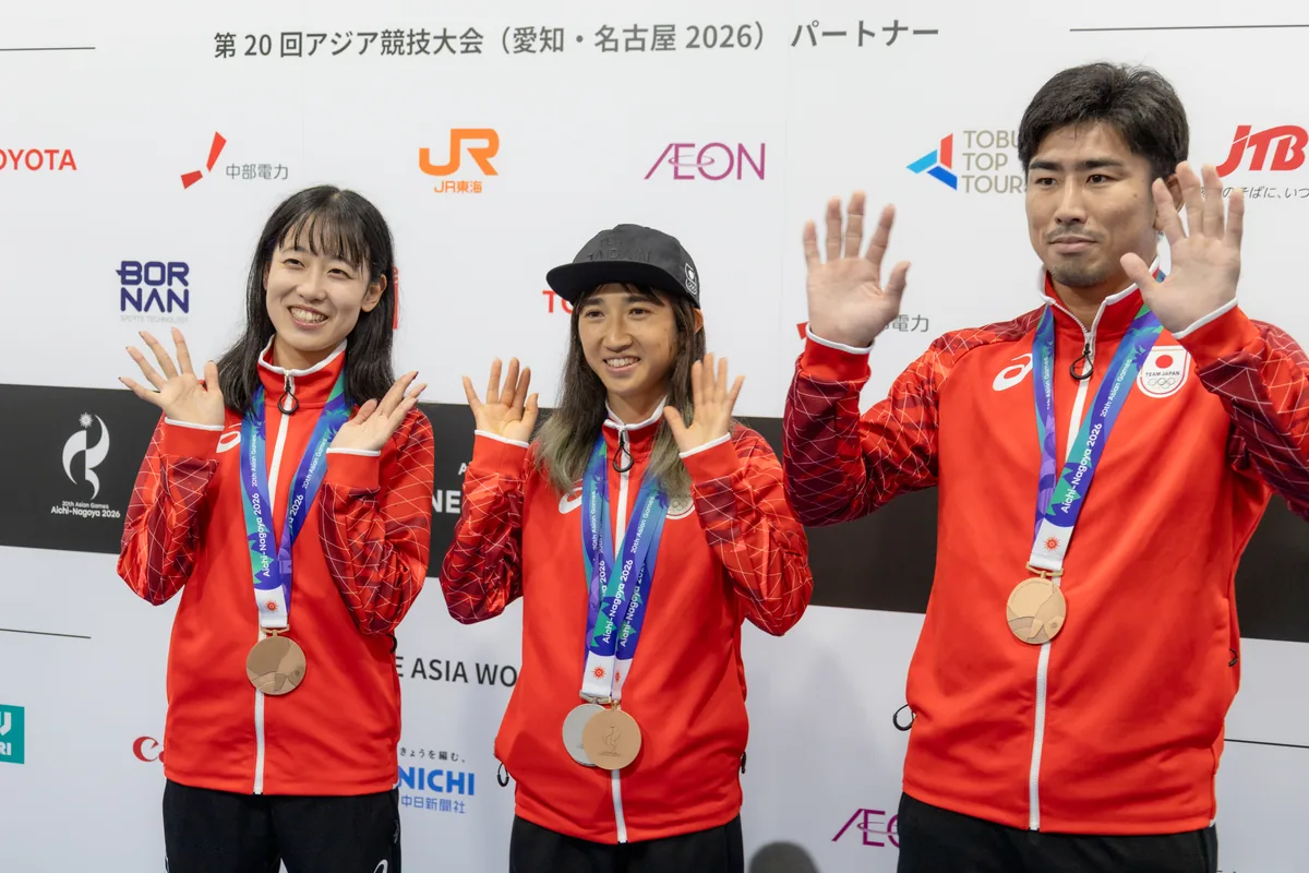 メダルを首にかけて手を振る梅野倖子選手、田中希実選手、大吉賢選手