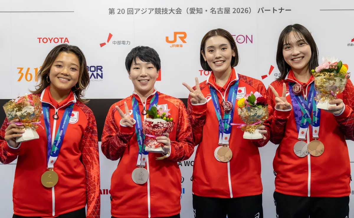 メダルと花束を手にピースサインをする池田美来選手、山口茜選手、岩永鈴選手、中西貴映選手
