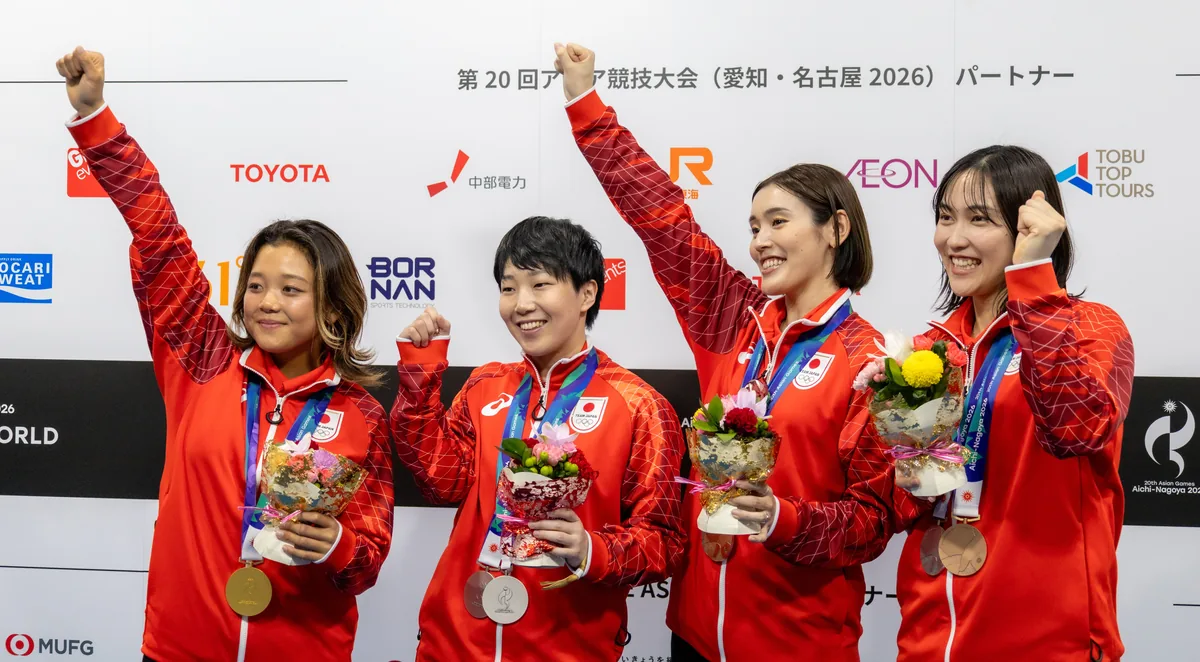 メダルと花束を手にガッツポーズをする池田美来選手、山口茜選手、岩永鈴選手、中西貴映選手