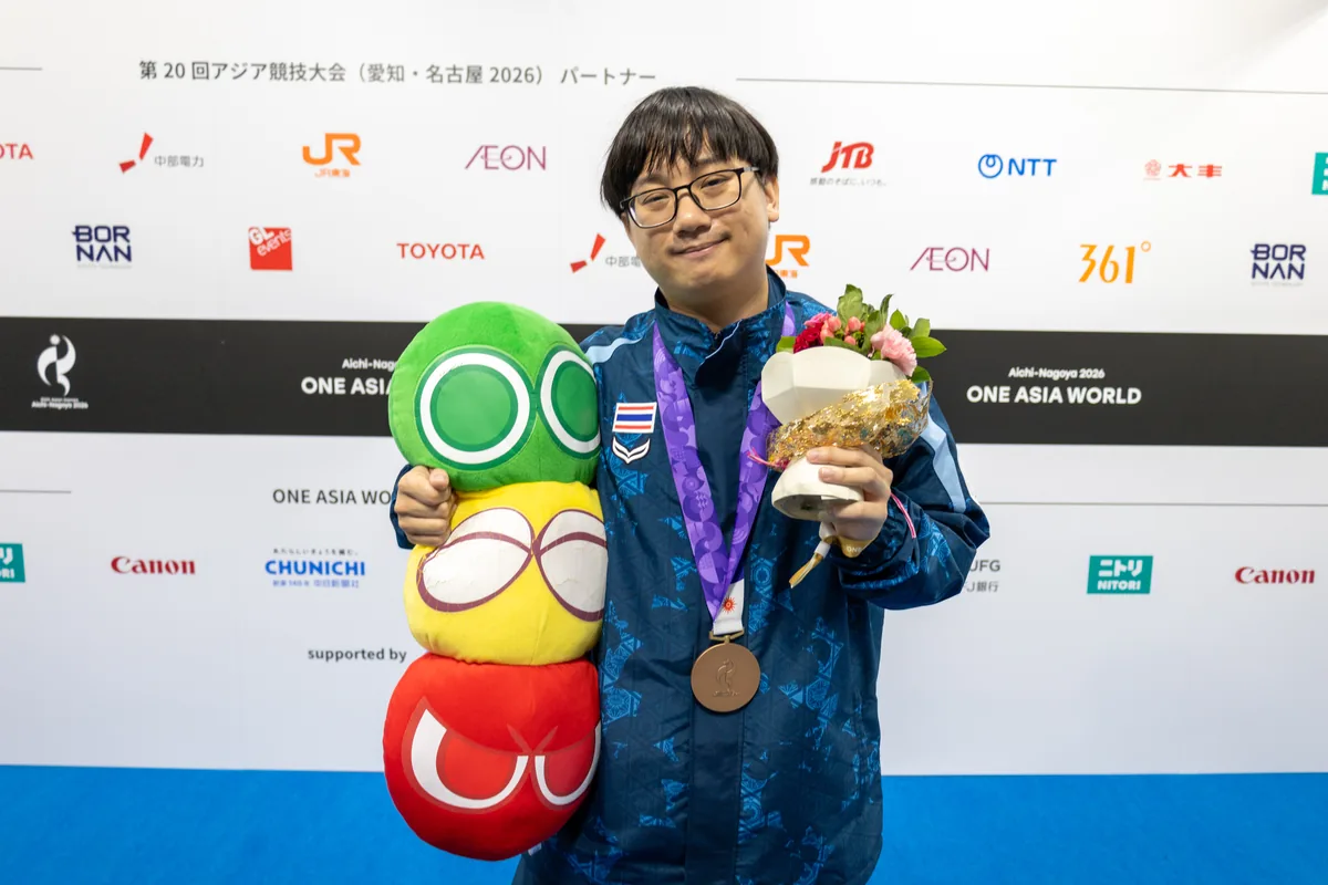 ぷよぷよのぬいぐるみと花束を手に、銅メダルをかけて笑顔を見せるタイのタナラック選手