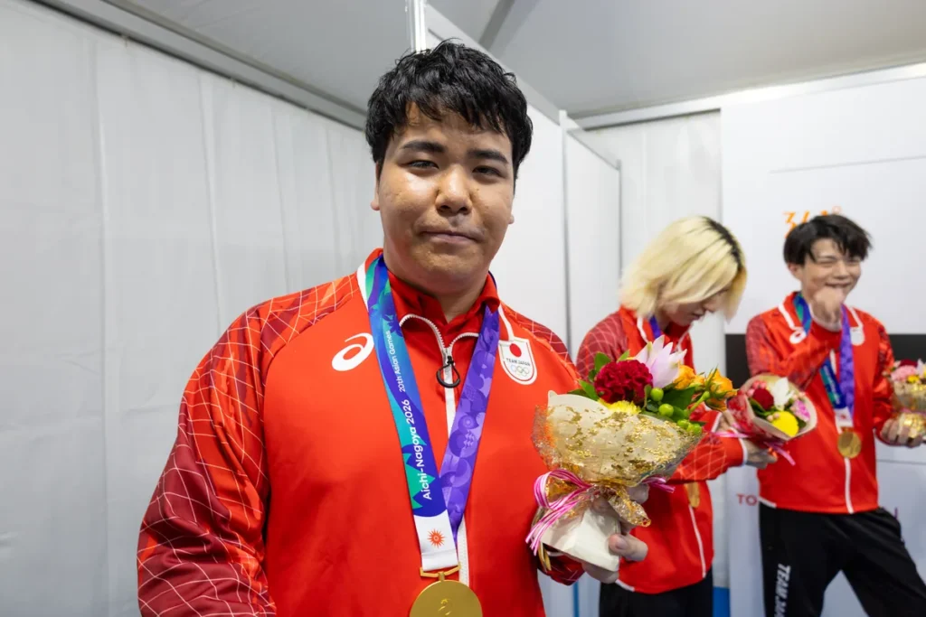 金メダルと花束を手にしたポケモンユナイト日本代表の佐藤博希選手