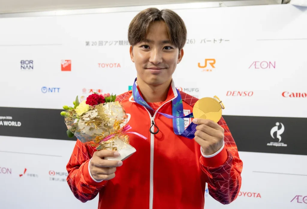 金メダルと花束を手にほほえむ競泳の西小野皓大選手