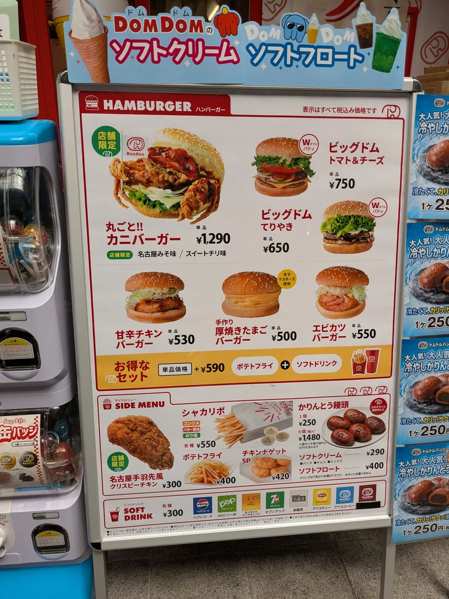 ドムドムハンバーガー大須万松寺通店のメニュー看板。店舗限定の丸ごとカニバーガー1,290円や名古屋手羽先風クリスピーチキン300円