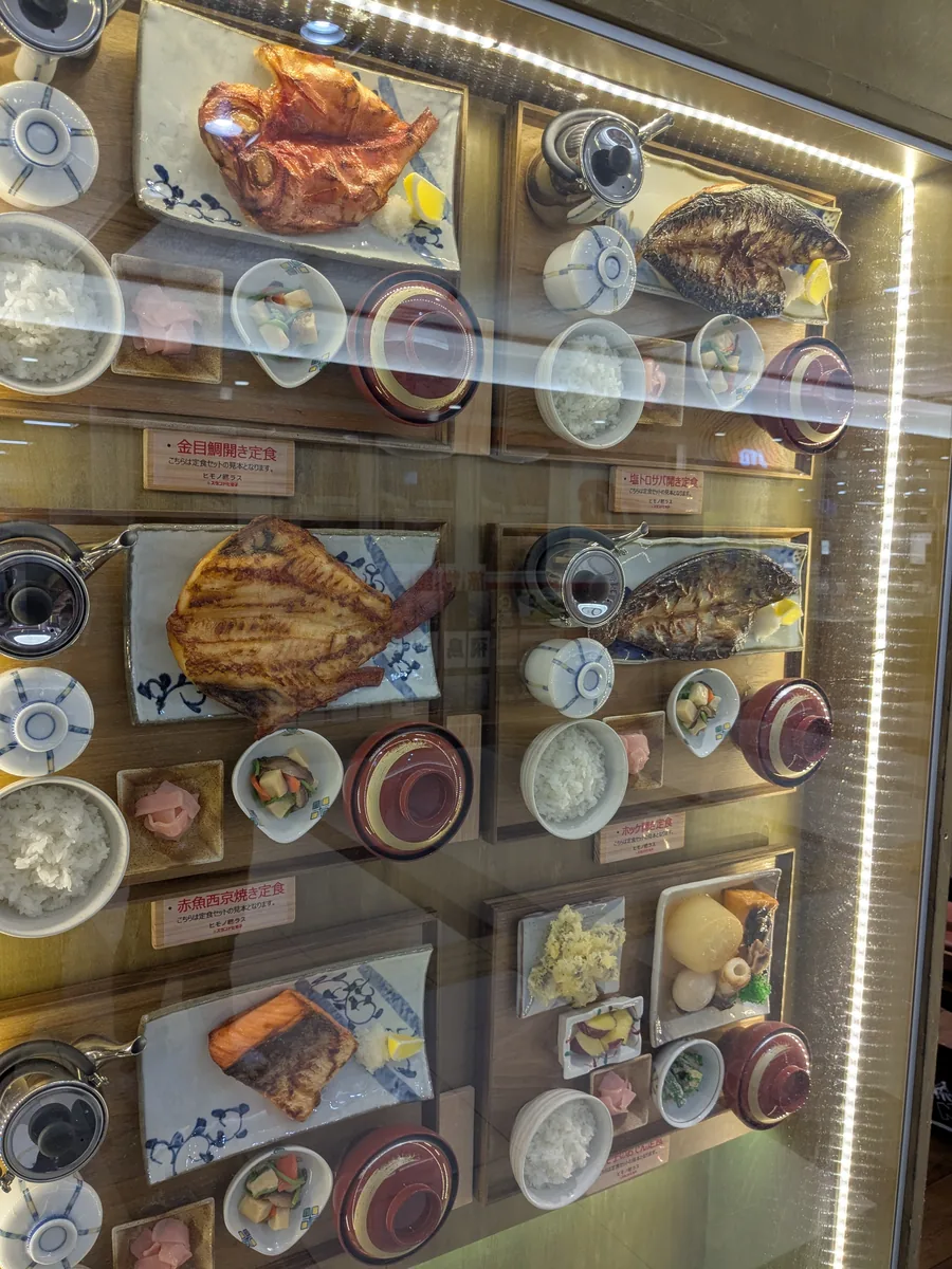 ヒモノ照ラス ユニモール店の店頭ショーケースに並ぶ金目鯛開き定食や赤魚西京焼き定食の食品サンプル