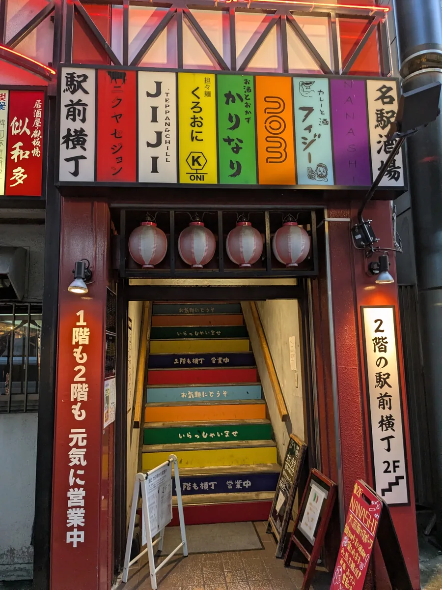 nomがある駅前横丁2階へ続くカラフルな階段の入口