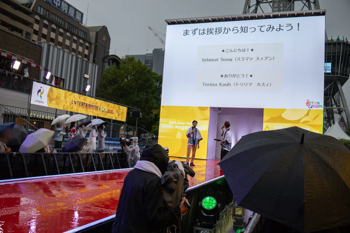 大型ビジョンに映る「まずは挨拶から知ってみよう!」のスライド。Selamat Siang(こんにちは)とTerima Kasih(ありがとう)を会場全体で練習した