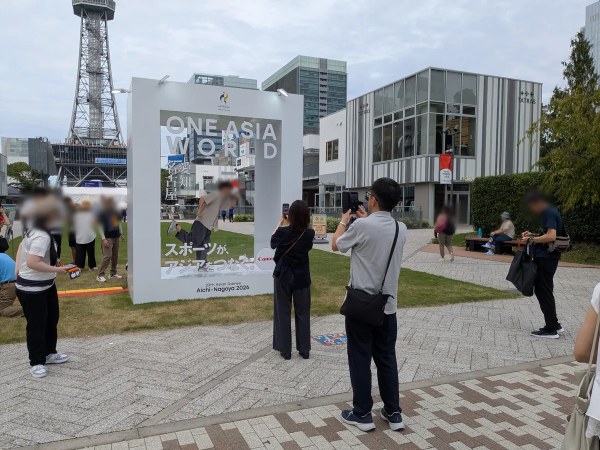 「スポーツが、アジアをつなぐ。」と書かれたONE ASIA WORLDの巨大フォトスポットで記念撮影する来場者