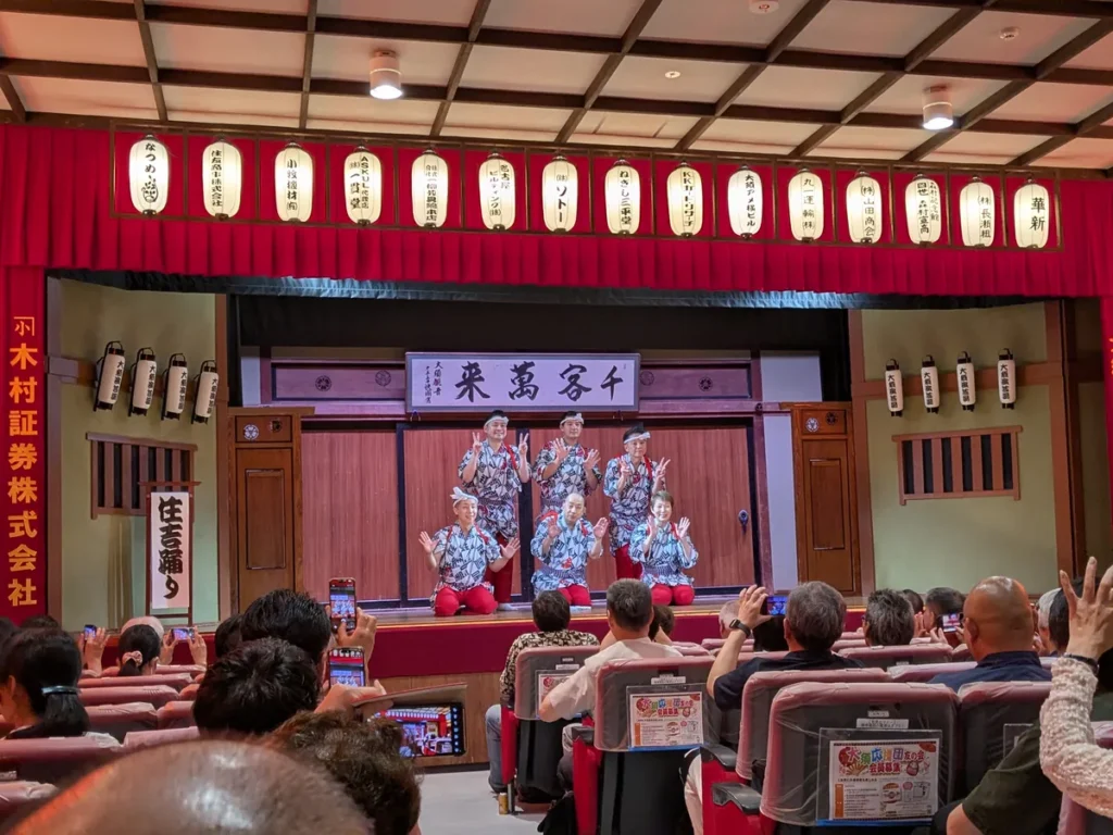 大須演芸場のフィナーレ「江戸住吉踊り」。揃いの浴衣に赤い袴の出演者6人が「千客萬来」の額の前で手を振る