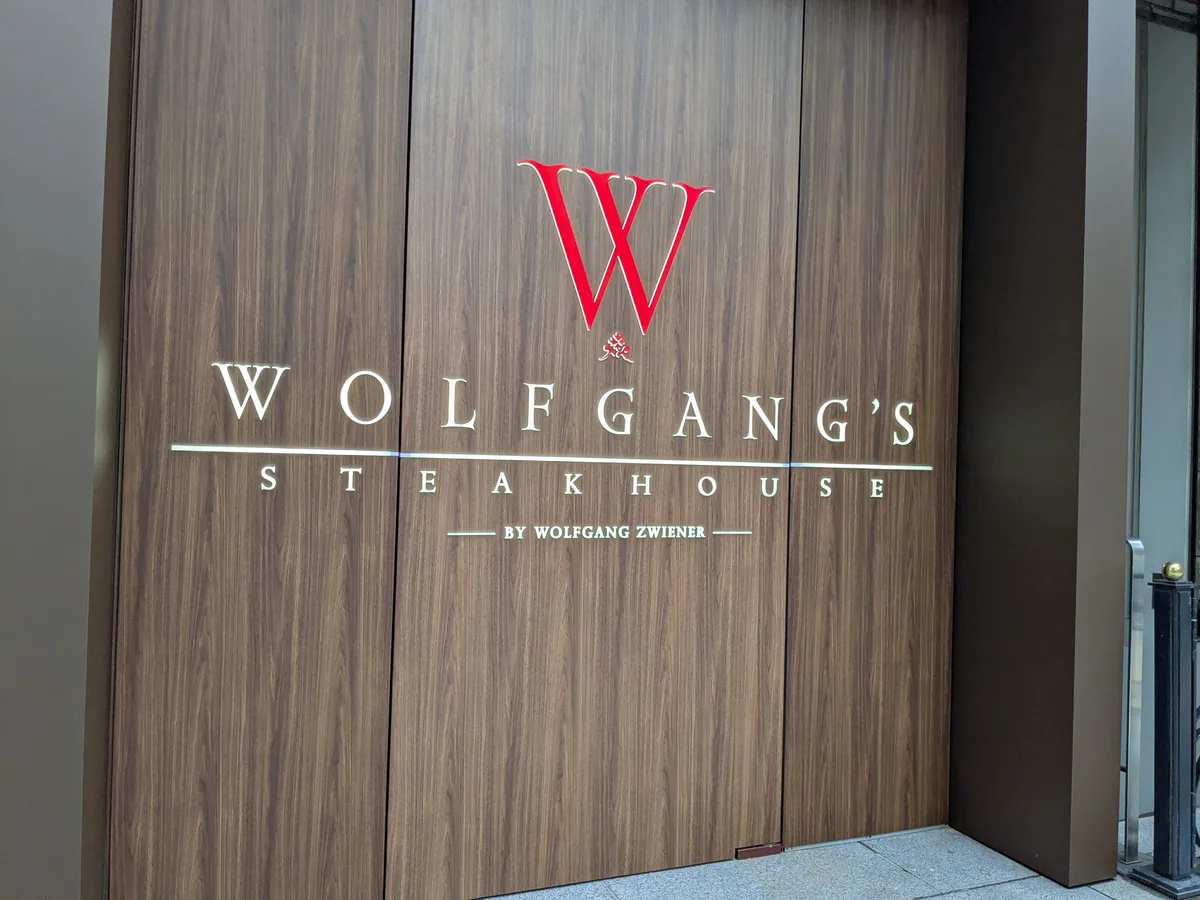 ウルフギャング・ステーキハウス名古屋店の木目の壁に掲げられたBY WOLFGANG ZWIENERのロゴサイン