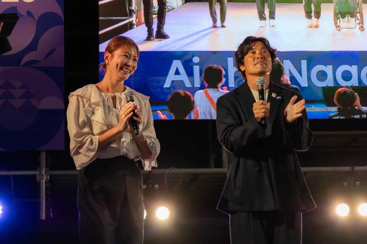 ONE HEART WORLDのステージで笑顔の青木愛さんと、拍手する大畑大介さん