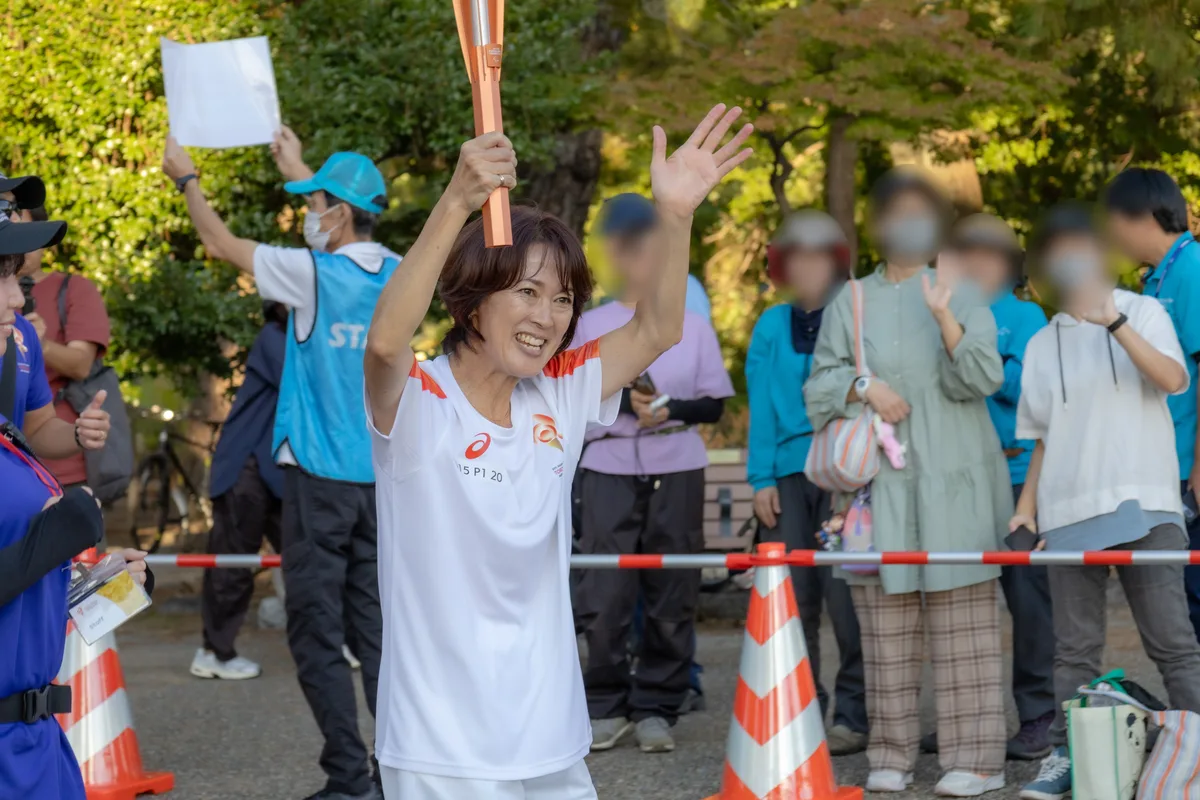 聖火を持って沿道に手を振る荒木絵里香さん