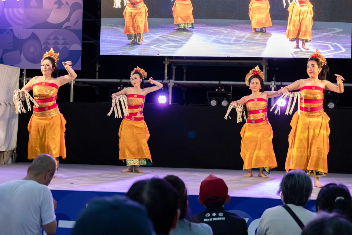アジアパラ ライブサイトのステージで踊るバリダンスの4人の踊り手。金色と赤の衣装で、客席は満席に近い