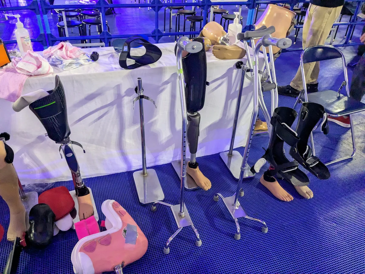 アジアパラ ライブサイトに展示された義足と装具。大腿義足、下腿義足、足首の装具、松葉づえ、子ども用のピンクの装具が並ぶ