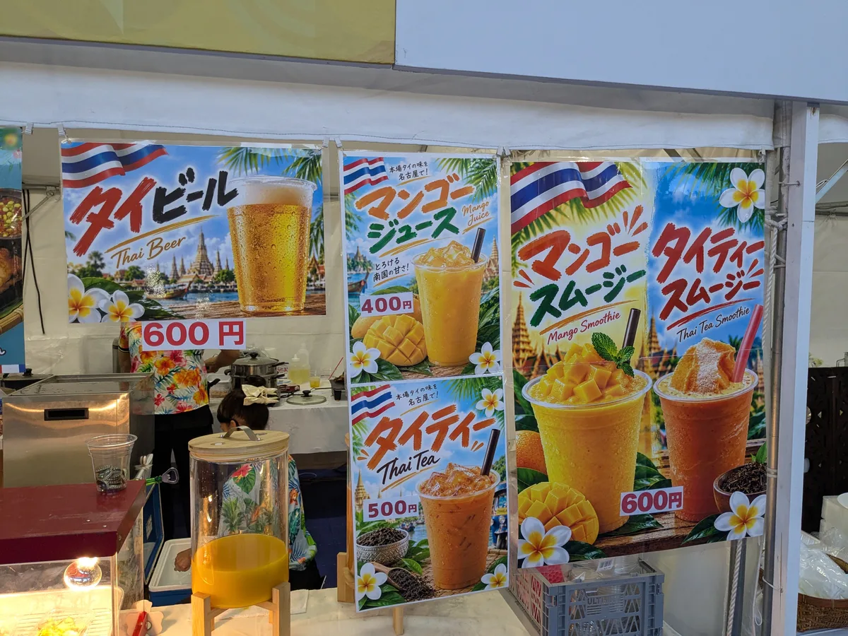 タイ料理ブースのドリンクメニュー。タイビール600円、マンゴージュース400円、タイティー500円、マンゴースムージーとタイティースムージー600円