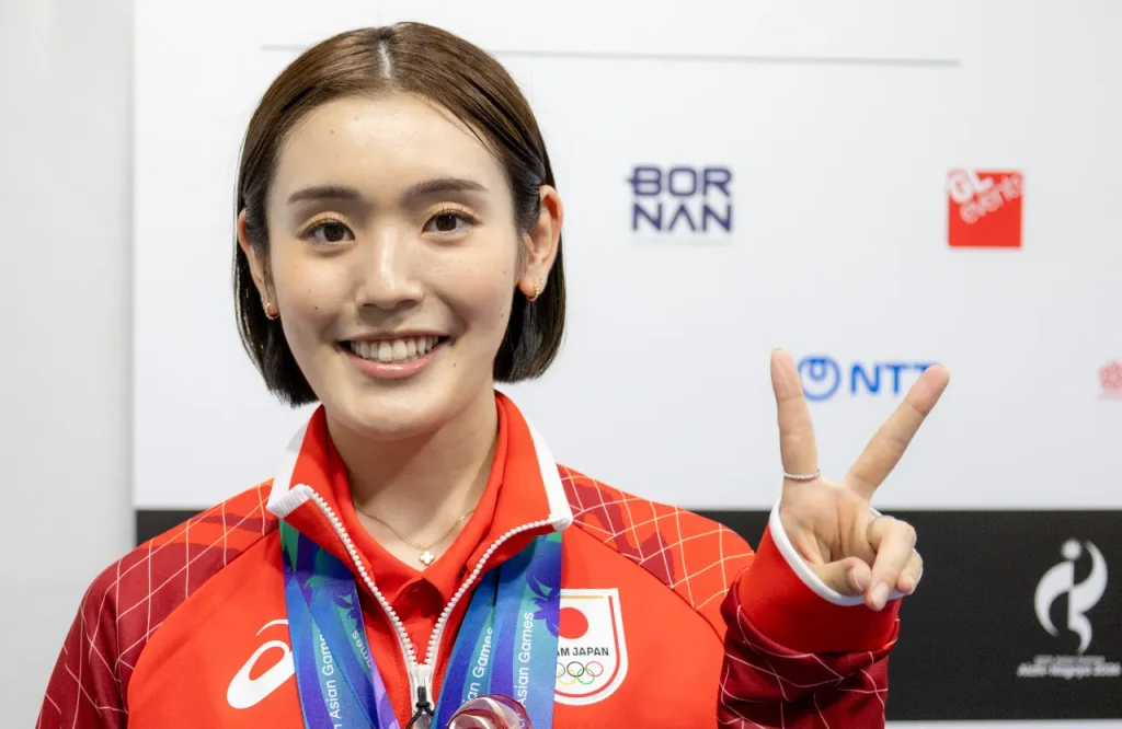 メダルを首にかけてピースサインをするバドミントンの岩永鈴選手