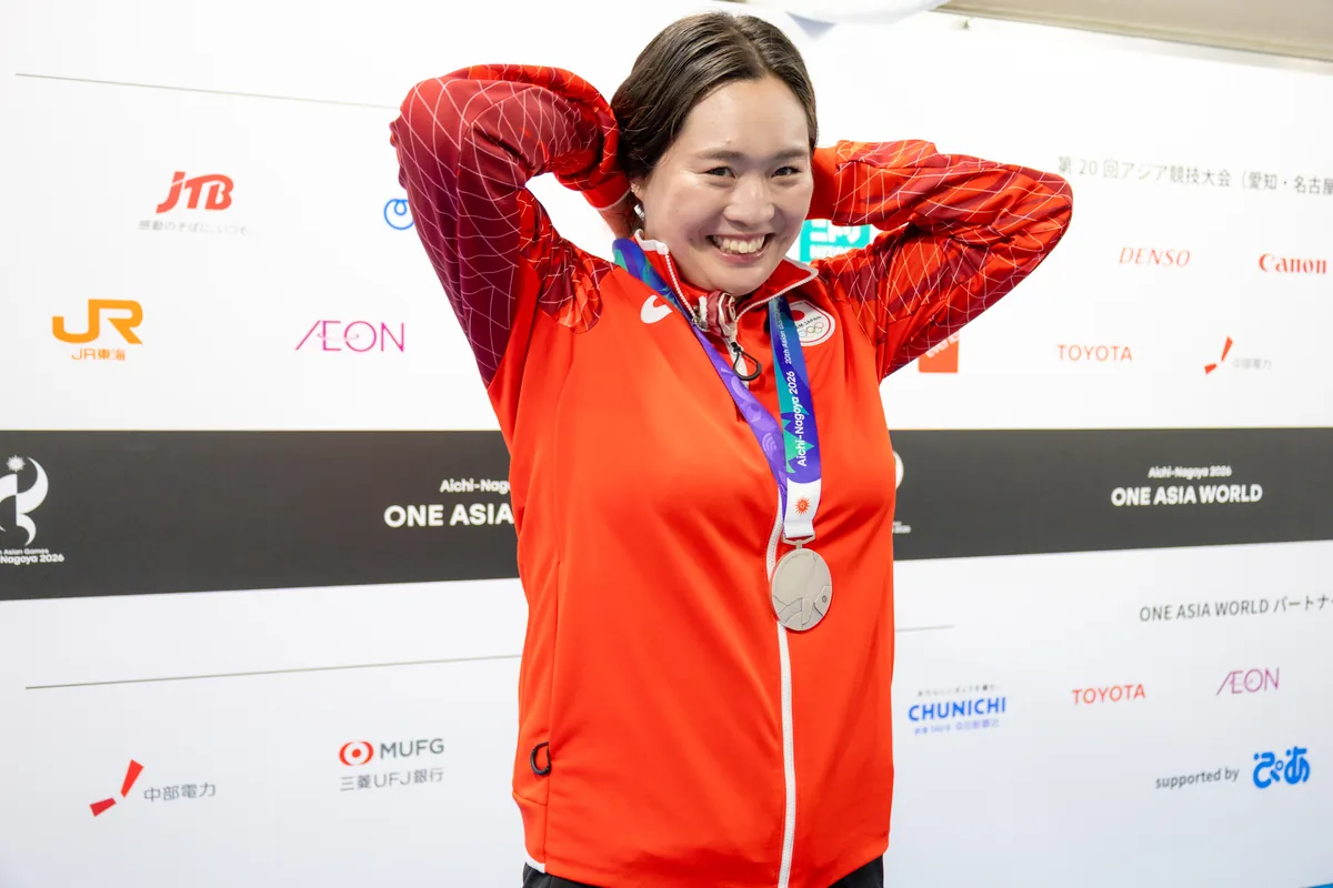 銀メダルを首にかけ、頭の後ろで両手を組んで笑う北口榛花選手