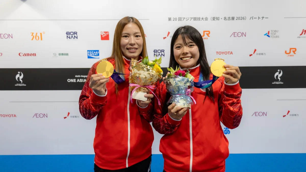 金メダルと花束を手にするラグビー7人制女子の大内田夏月選手(左)と須田倫代選手