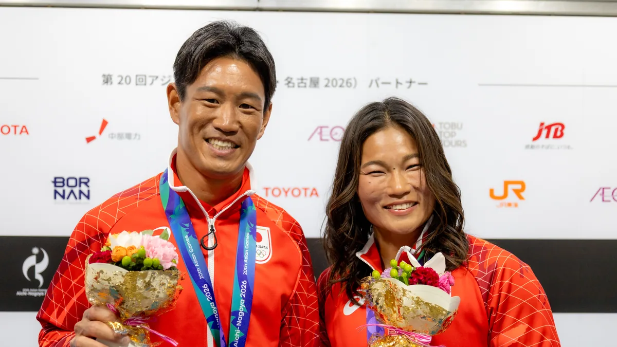 花束を手に笑顔を見せるセーリングの磯崎哲也選手と関友里恵選手