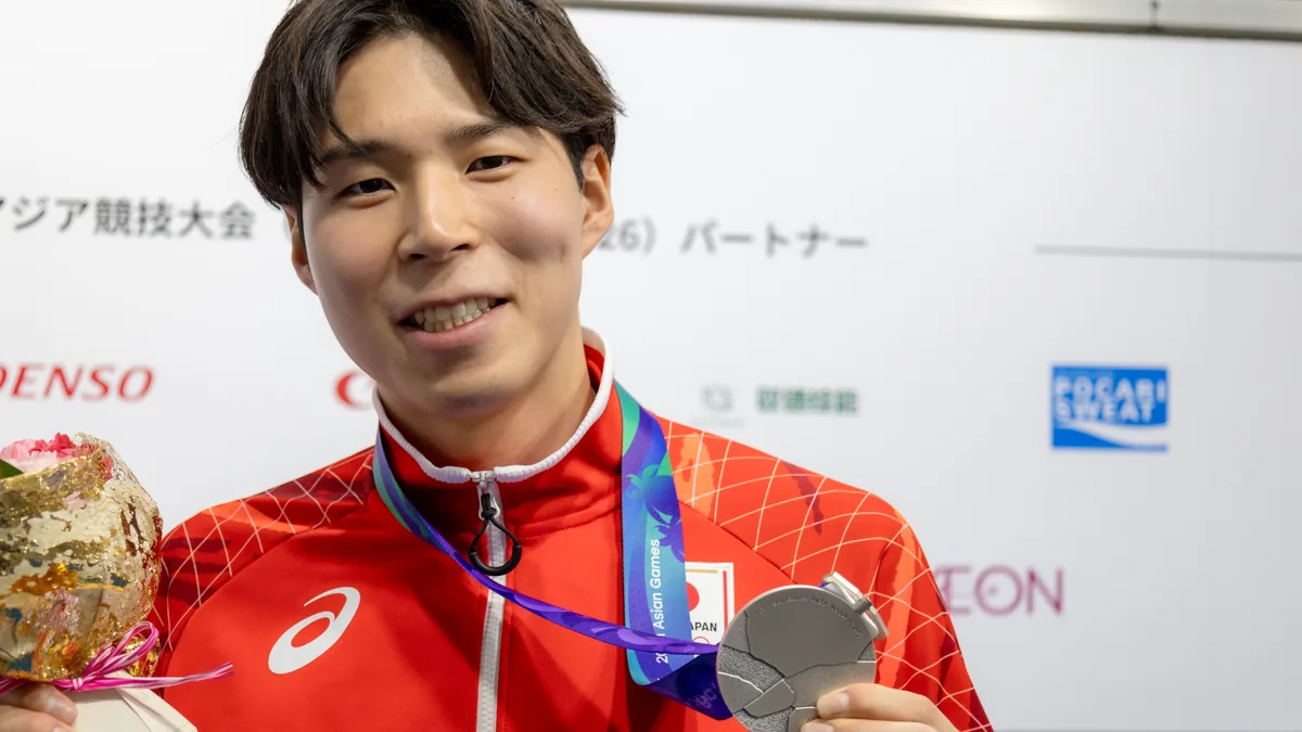 銀メダルと花束を手に笑顔を見せるバレーボールの新井雄大選手