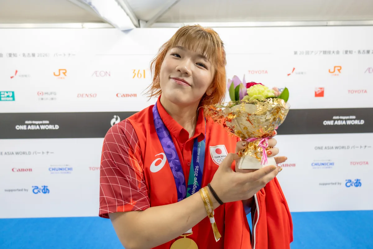 金メダルをかけ、花束を手に笑顔を見せるレスリングの鏡優翔選手