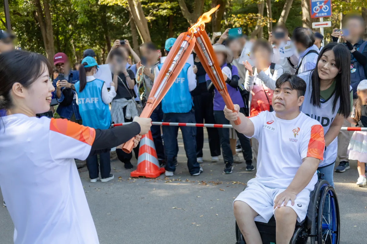 前のランナーから聖火を受け取る大堂秀樹さん