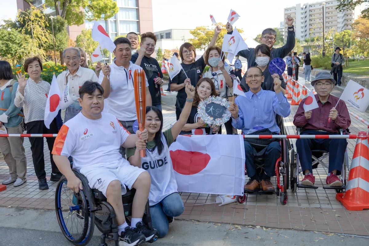 応援に駆けつけた家族や仲間と日の丸を掲げる大堂秀樹さん
