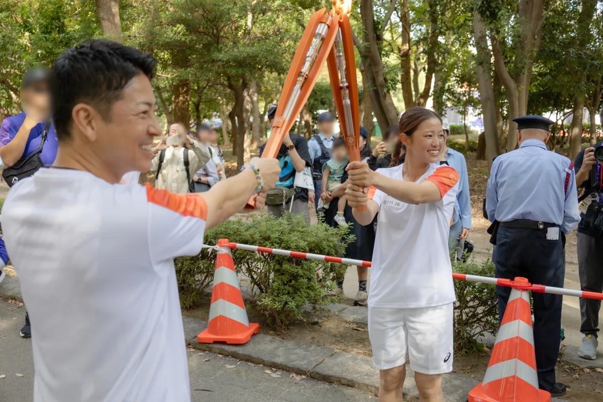 舟阪育枝さんから富川悠太さんへ聖火を受け渡す瞬間