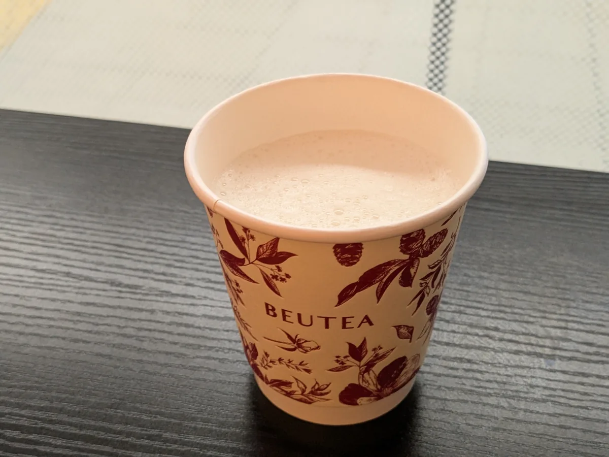 BEUTEAメイチカ店のジャスミンミルクティー(ホット・Sサイズ539円)。蓋なしの紙カップで表面に細かい泡が立つ