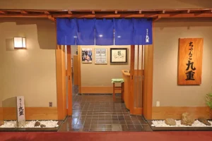 アパホテル名古屋栄駅前EXCELLENT 5階にあるちゃんこ九重の入口。紺ののれんと木の看板