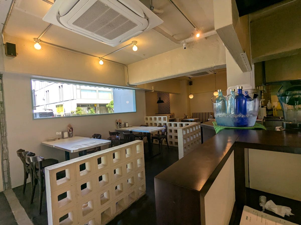 白い壁とブロック塀の仕切りが並ぶCHEDDARの店内のテーブル席とカウンター