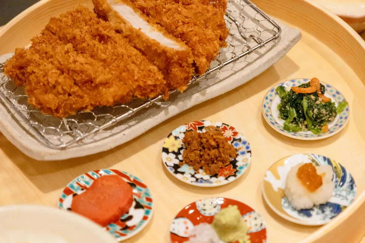 網にのったCHITAKAのロースかつ。切り口から白い断面がのぞき、手前に豆皿が並ぶ