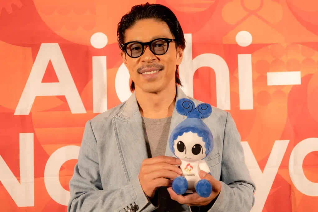 大会マスコットのウズミンのぬいぐるみを持って笑顔を見せるEXILEの松本利夫さん