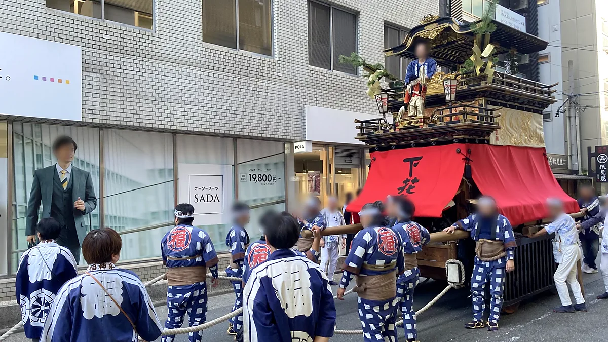 花車神明社祭で名駅のビル街を曳かれる二福神車。正面の赤い幕に「下花」の文字