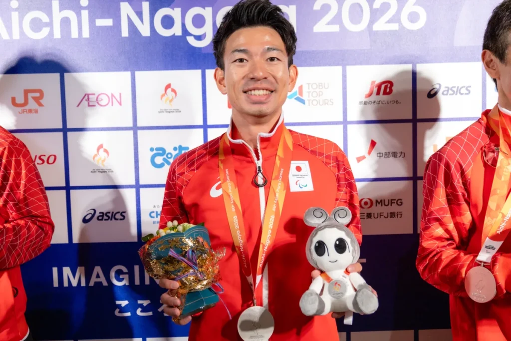 ミックスゾーンで銀メダルと花束、ウズミンのぬいぐるみを手にするパラ陸上の石田駆選手