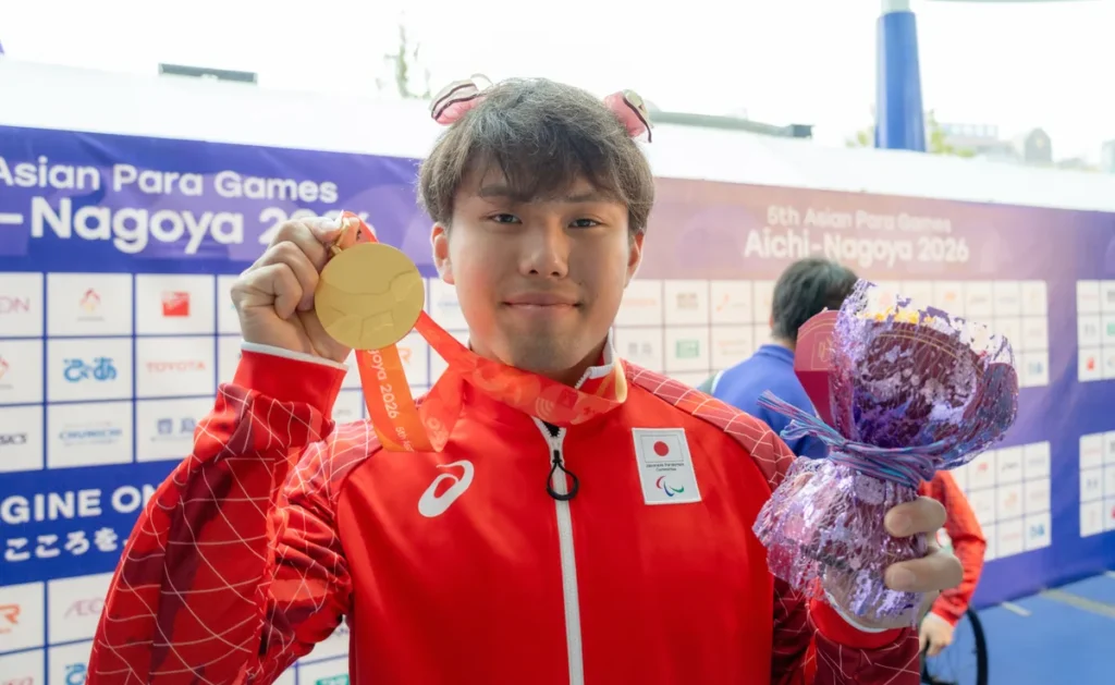 花の飾りを頭に付けて金メダルと花束を掲げる岩田晋作選手