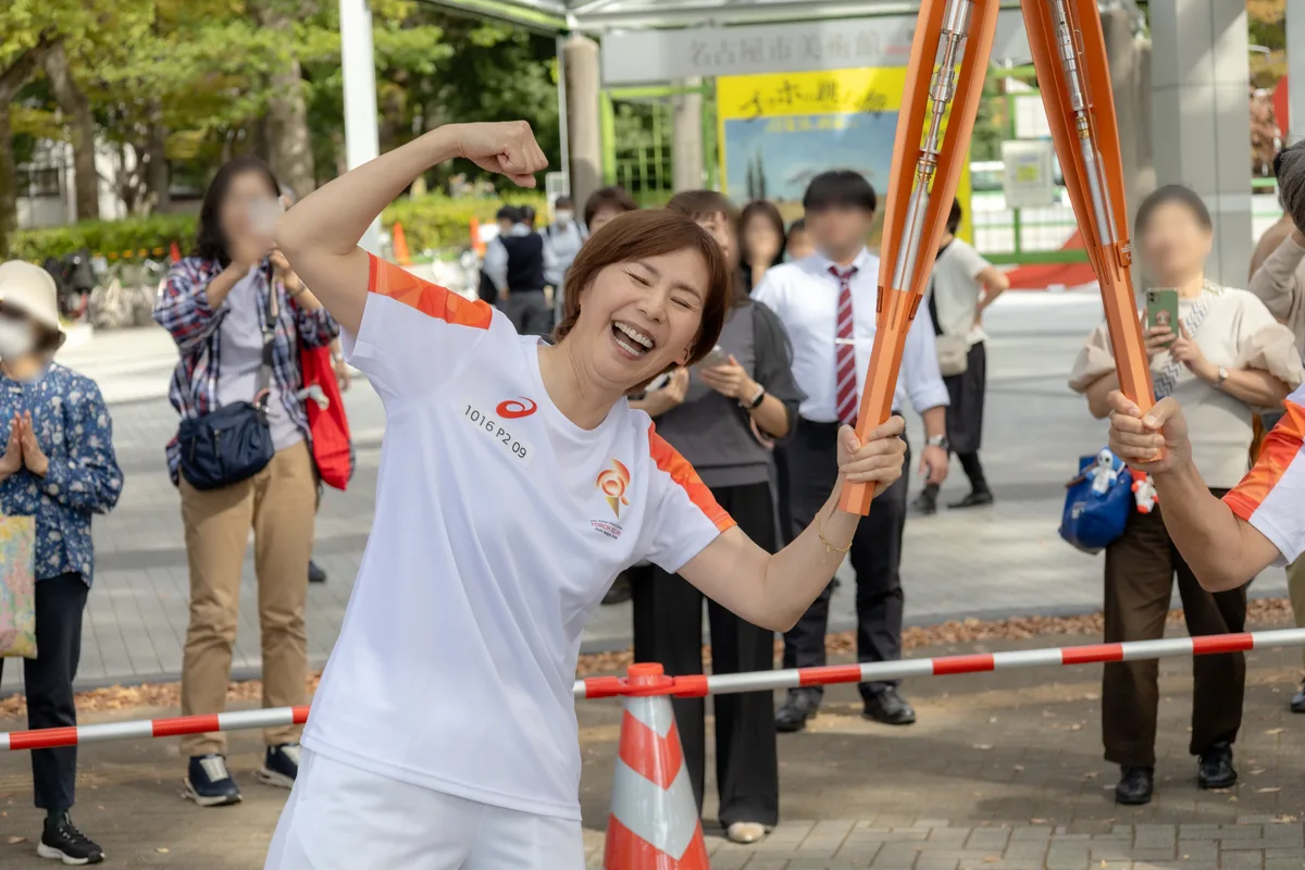 走り終えて笑顔でトーチを掲げる陣内貴美子さん