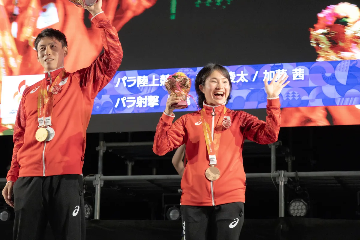 花束を手に笑う加藤茜選手。左は花束を掲げる福永凌太選手