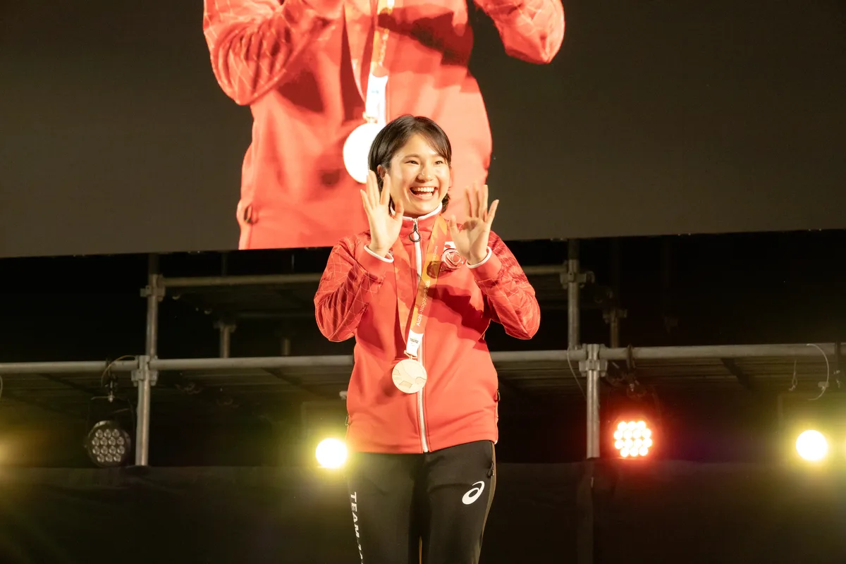 銅メダルを掛けてステージで手を振る加藤茜選手