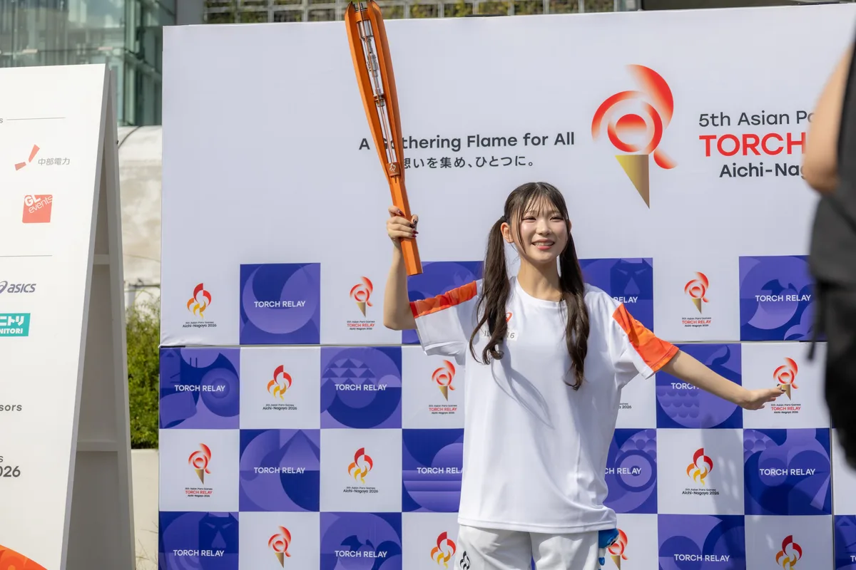 ゴール後、フォトボードの前で聖火を掲げる河村優愛さん