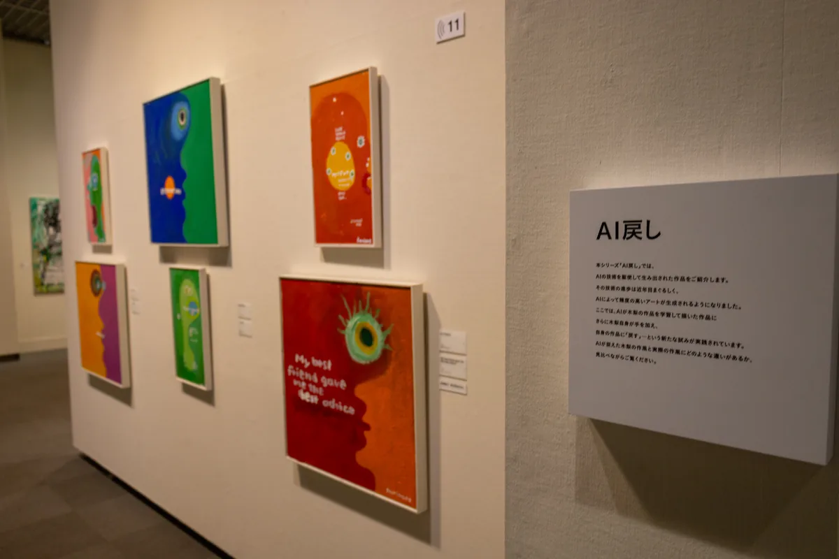 AIが描いた絵に木梨憲武さんが手を加えた「AI戻し」シリーズの作品と説明パネル