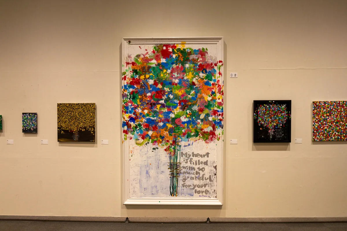 色とりどりの絵の具を重ねて描いた大きな木の作品と、その両側に並ぶ小さな作品（木梨憲武展 名古屋会場）