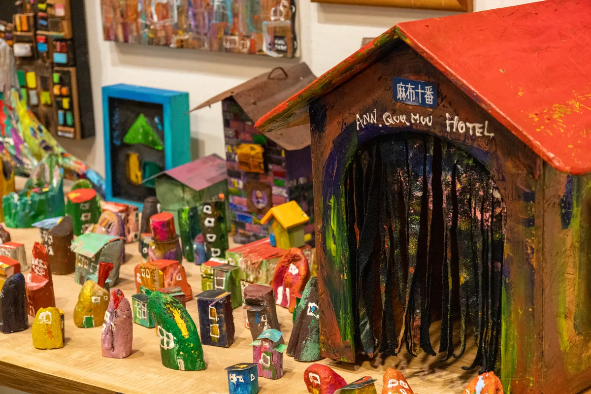 木で作った色とりどりの小さな家と赤い屋根の大きな家が並ぶ木梨憲武さんの立体作品